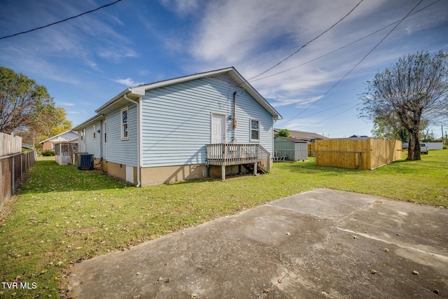 back of property featuring central air condition unit, a lawn, and fence