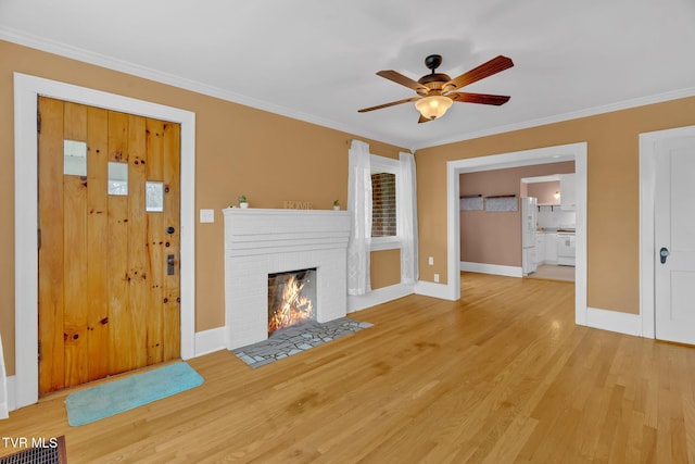 unfurnished living room featuring crown molding, light wood-style flooring, a fireplace, and baseboards