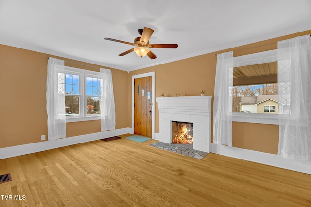 unfurnished living room featuring visible vents, ornamental molding, wood finished floors, a fireplace, and baseboards