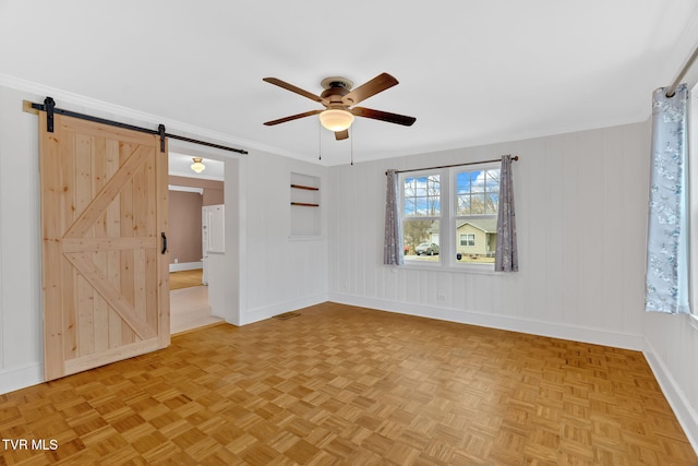 unfurnished room with baseboards, visible vents, ornamental molding, ceiling fan, and a barn door