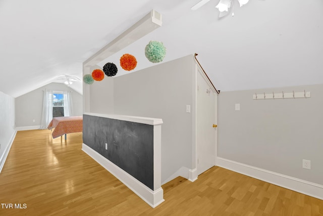 additional living space featuring baseboards, light wood-style flooring, a ceiling fan, and vaulted ceiling