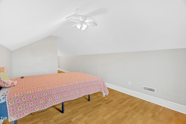 bedroom with visible vents, baseboards, vaulted ceiling, wood finished floors, and a ceiling fan