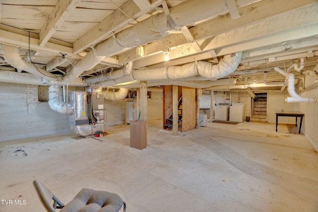 unfinished below grade area with water heater, heating unit, and separate washer and dryer