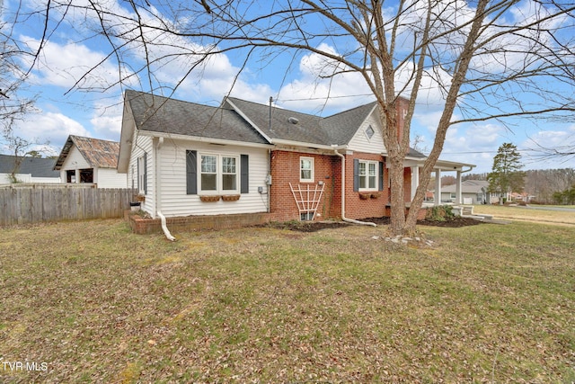 view of front of house with brick siding, fence, roof with shingles, a front yard, and a chimney