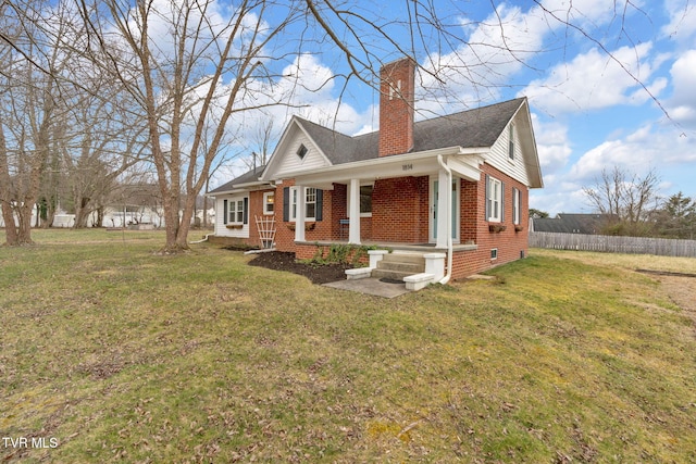 view of front of property featuring a porch, fence, a front yard, brick siding, and a chimney