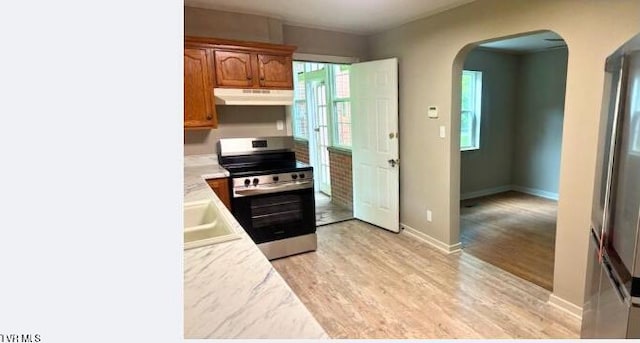 804 E Maple St, Johnson City, TN 37601 - kitchen with electric range, under cabinet range hood, arched walkways, light countertops, and light wood-style floors