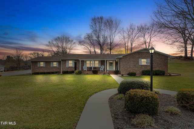 view of front facade with brick siding and a yard