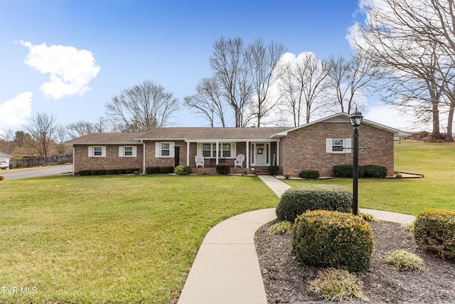 single story home with a front lawn, a porch, and brick siding