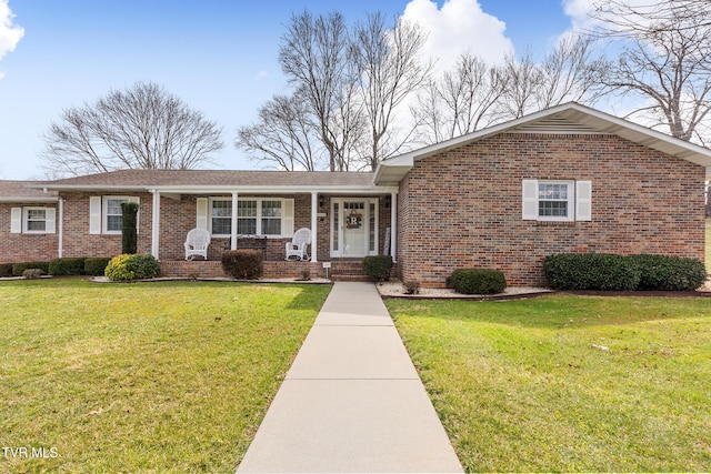 ranch-style home featuring a front yard, covered porch, and brick siding