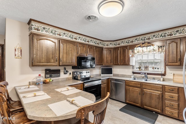 kitchen with stainless steel appliances, a peninsula, a sink, visible vents, and light countertops