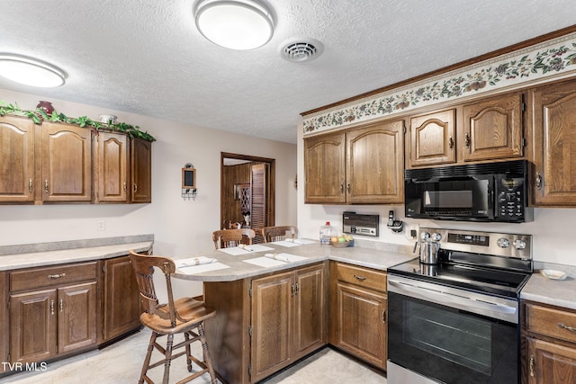 kitchen featuring black microwave, a peninsula, a breakfast bar, light countertops, and stainless steel electric range