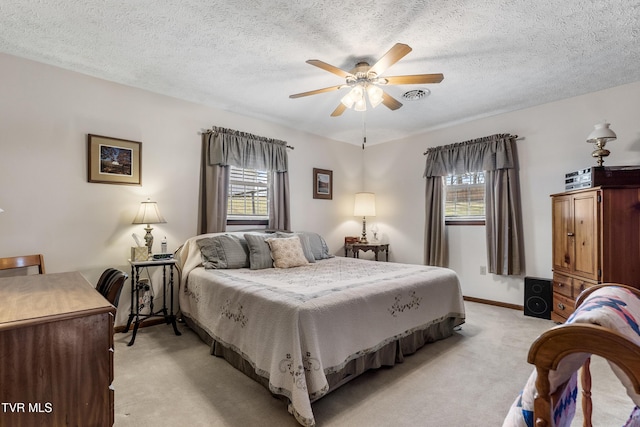 bedroom featuring baseboards, visible vents, light colored carpet, ceiling fan, and a textured ceiling