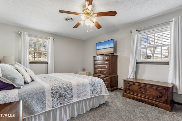 bedroom with a textured ceiling, ceiling fan, carpet flooring, and visible vents