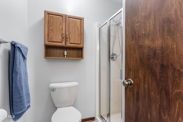 bathroom featuring toilet and a shower stall