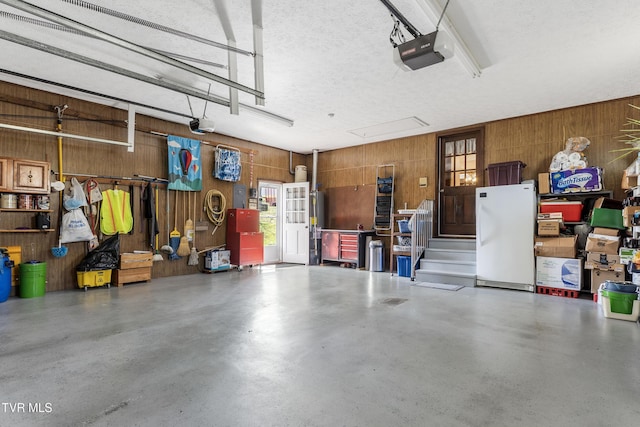 garage featuring wood walls, freestanding refrigerator, and a garage door opener