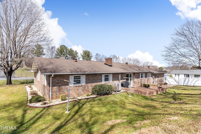 rear view of property with a lawn, a chimney, roof with shingles, fence, and brick siding