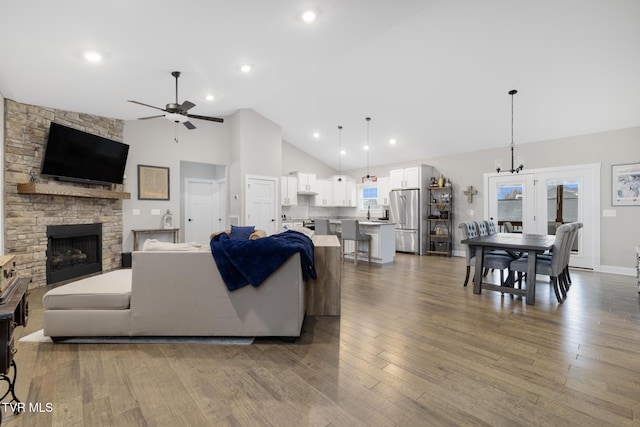 living room featuring ceiling fan, high vaulted ceiling, a fireplace, and hardwood / wood-style flooring