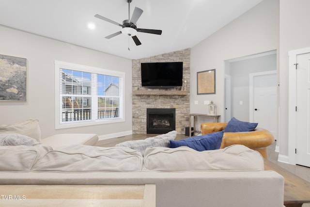 living area featuring a fireplace, ceiling fan, vaulted ceiling, wood finished floors, and baseboards