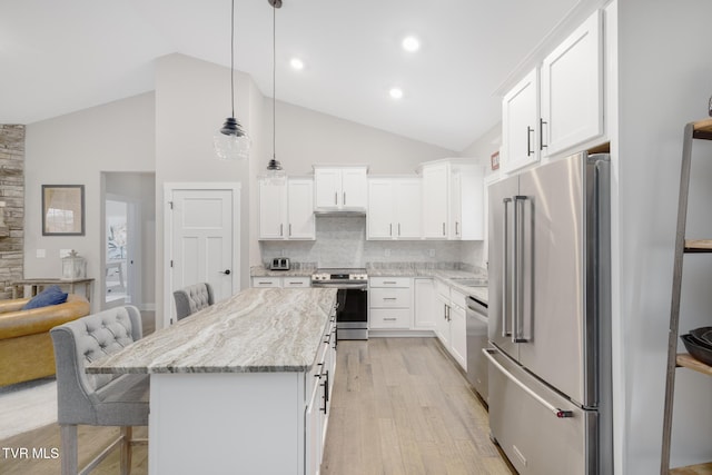 kitchen with light wood finished floors, a breakfast bar area, stainless steel appliances, decorative backsplash, and a kitchen island