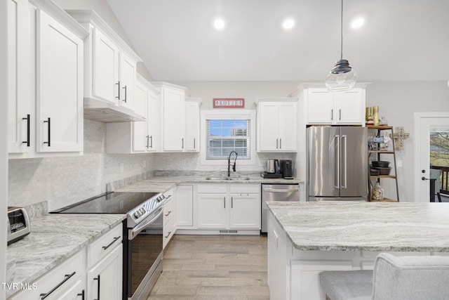 kitchen featuring white cabinets, a sink, stainless steel appliances, light wood-type flooring, and backsplash