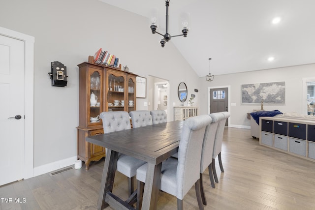 dining space featuring high vaulted ceiling, a notable chandelier, visible vents, baseboards, and light wood finished floors