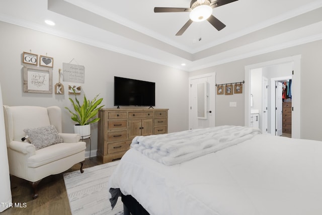 bedroom with ornamental molding, wood finished floors, a raised ceiling, and recessed lighting