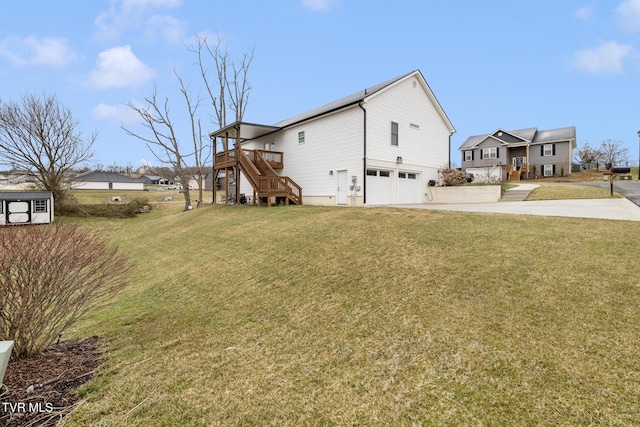 view of side of home with driveway, stairway, an attached garage, and a lawn