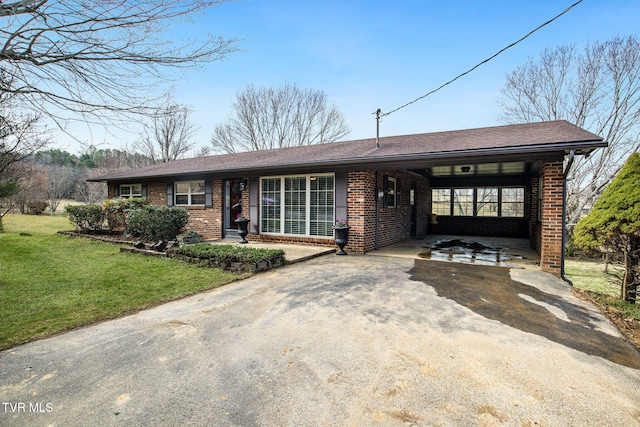 single story home with aphalt driveway, an attached carport, a front yard, and brick siding