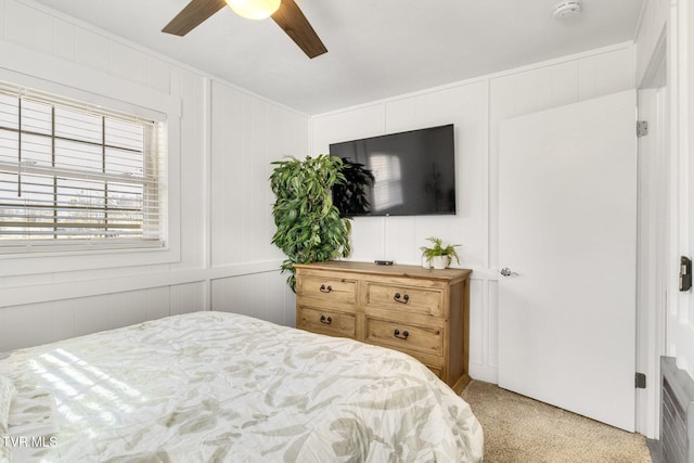 bedroom featuring a decorative wall, a ceiling fan, and light colored carpet