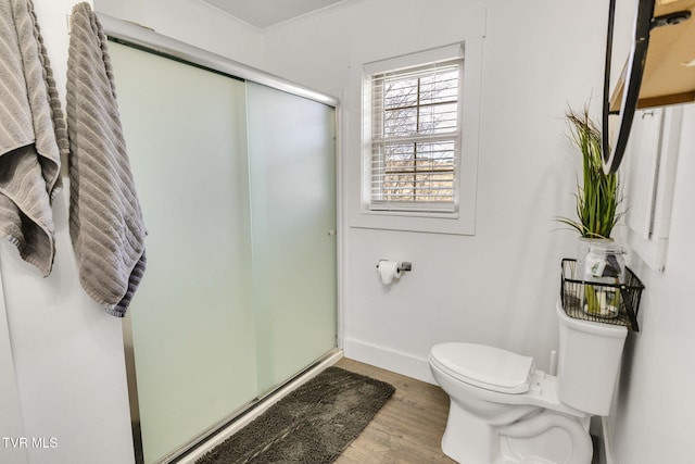 full bath featuring toilet, ornamental molding, a stall shower, wood finished floors, and baseboards