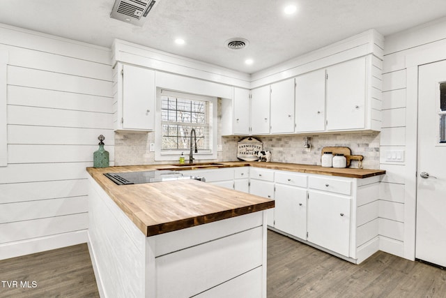 kitchen featuring visible vents, wooden counters, a sink, and black electric cooktop