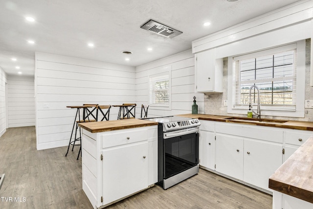 kitchen with stainless steel electric range oven, wood counters, visible vents, and a sink