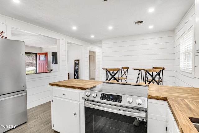 kitchen featuring stainless steel appliances, butcher block counters, visible vents, light wood-style flooring, and white cabinets