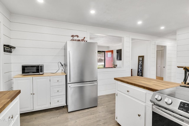 kitchen with appliances with stainless steel finishes, light wood-type flooring, white cabinets, and wood counters