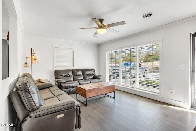 living area featuring a ceiling fan, visible vents, crown molding, and wood finished floors