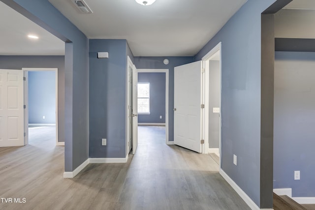 corridor featuring wood finished floors, visible vents, and baseboards