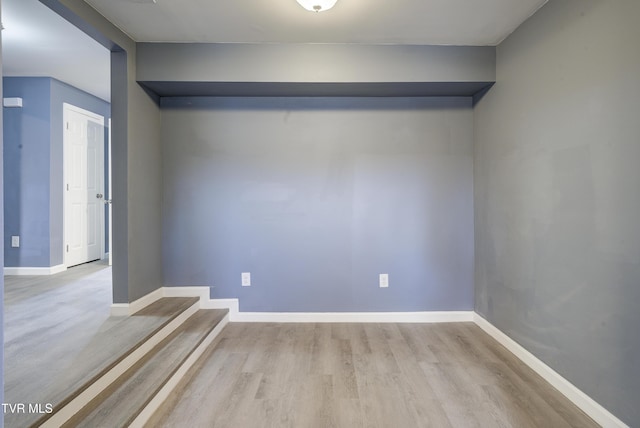 spare room featuring baseboards and wood finished floors