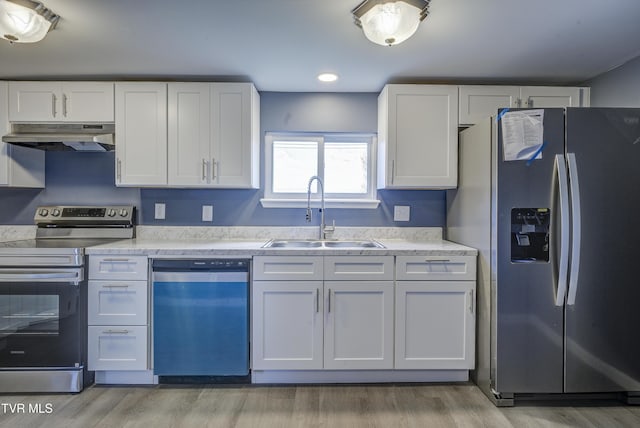 kitchen with under cabinet range hood, appliances with stainless steel finishes, white cabinets, and a sink