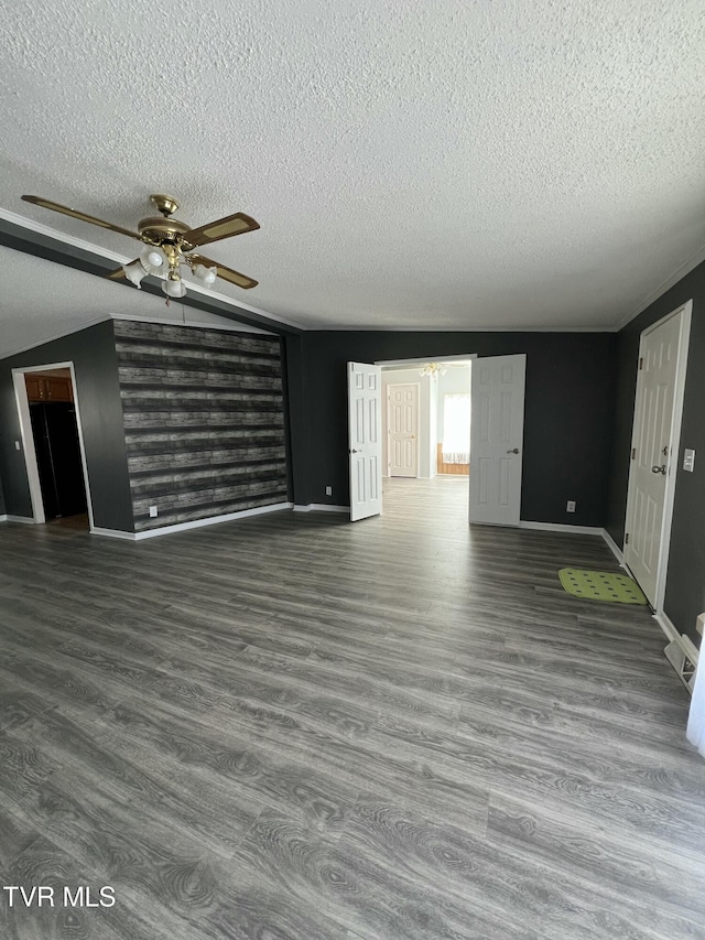 unfurnished living room featuring baseboards, ceiling fan, wood finished floors, vaulted ceiling, and a textured ceiling