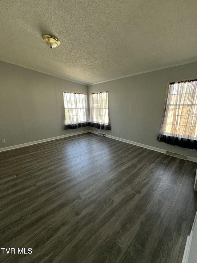 spare room with dark wood-style floors, crown molding, a textured ceiling, and baseboards