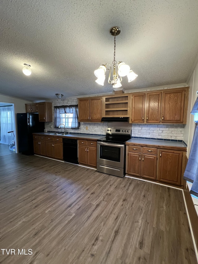 kitchen featuring dark countertops, dark wood-style flooring, black appliances, a chandelier, and a sink