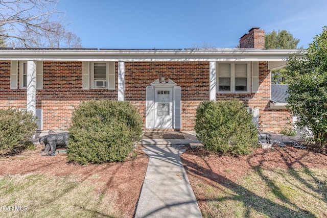 doorway to property featuring brick siding and a chimney