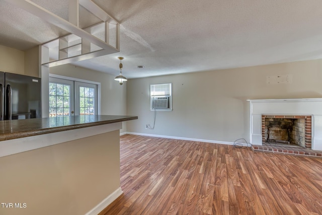 kitchen featuring french doors, a fireplace, freestanding refrigerator, wood finished floors, and plenty of natural light