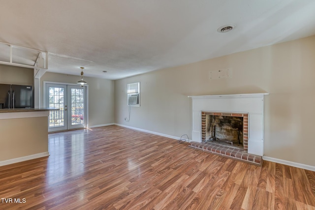 unfurnished living room with a fireplace, visible vents, wood finished floors, and french doors