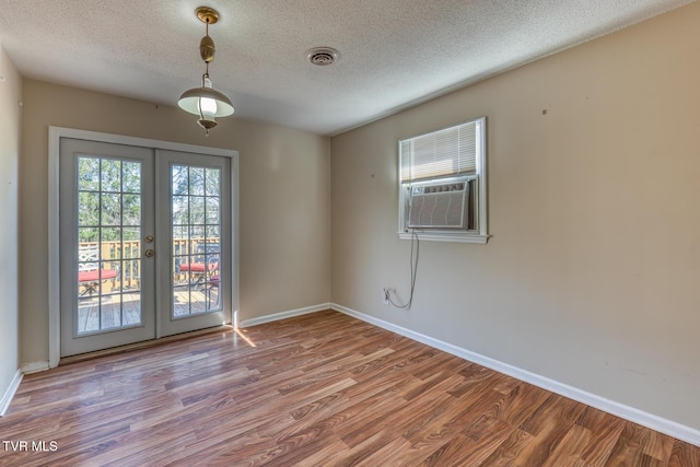 empty room with baseboards, visible vents, wood finished floors, and french doors