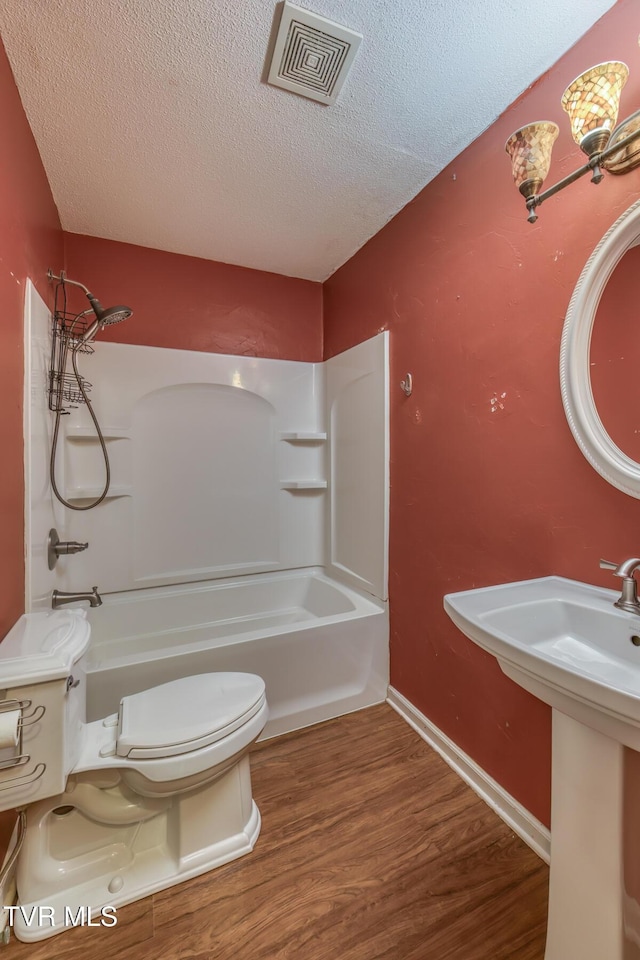 full bathroom featuring visible vents, toilet, wood finished floors, bathtub / shower combination, and a textured ceiling