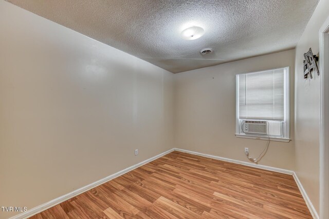 empty room with light wood-style floors, visible vents, baseboards, and a textured ceiling