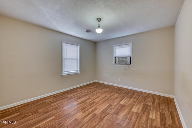 unfurnished room featuring visible vents, cooling unit, wood finished floors, and a wealth of natural light