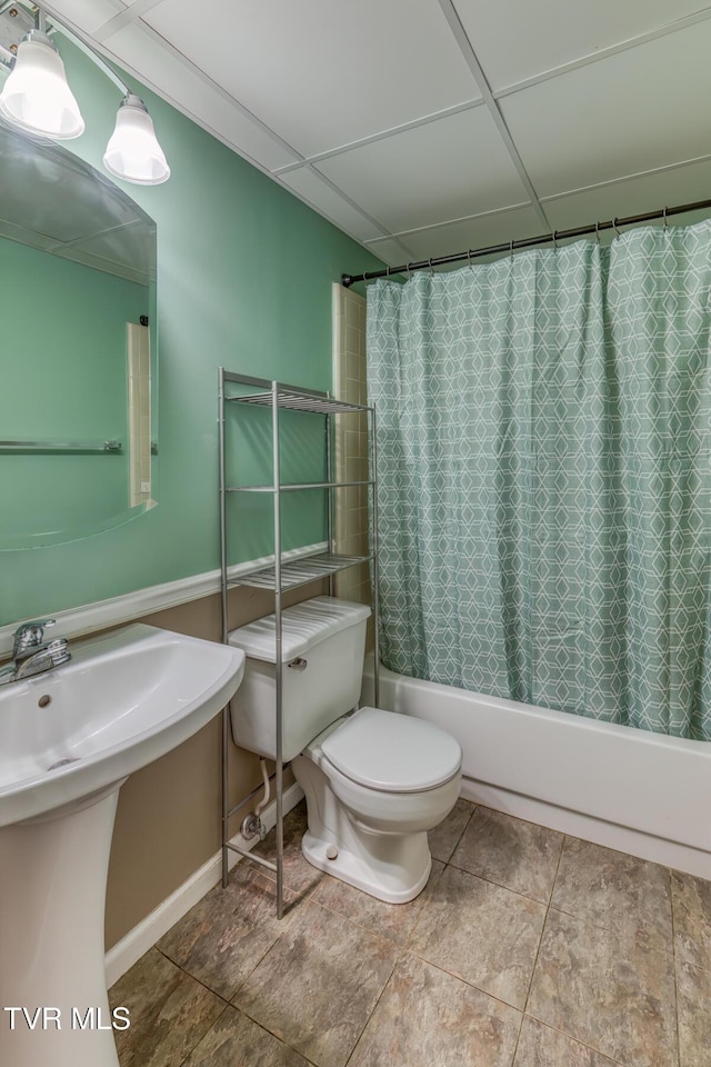 bathroom featuring tile patterned flooring, a paneled ceiling, toilet, a sink, and shower / bathtub combination with curtain