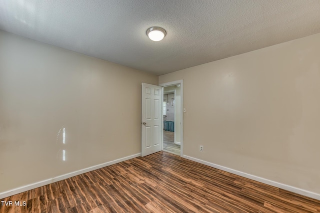 unfurnished room featuring a textured ceiling, dark wood-type flooring, and baseboards